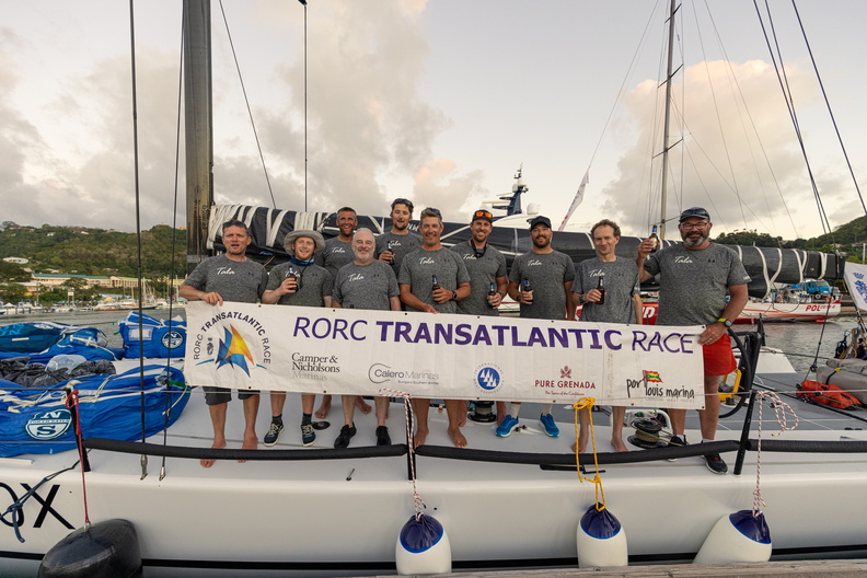 Tala crew pose with their finish banner on board the Botin 52