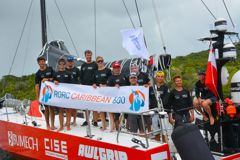 Crew pose with the race banner on board Wind Whisper
